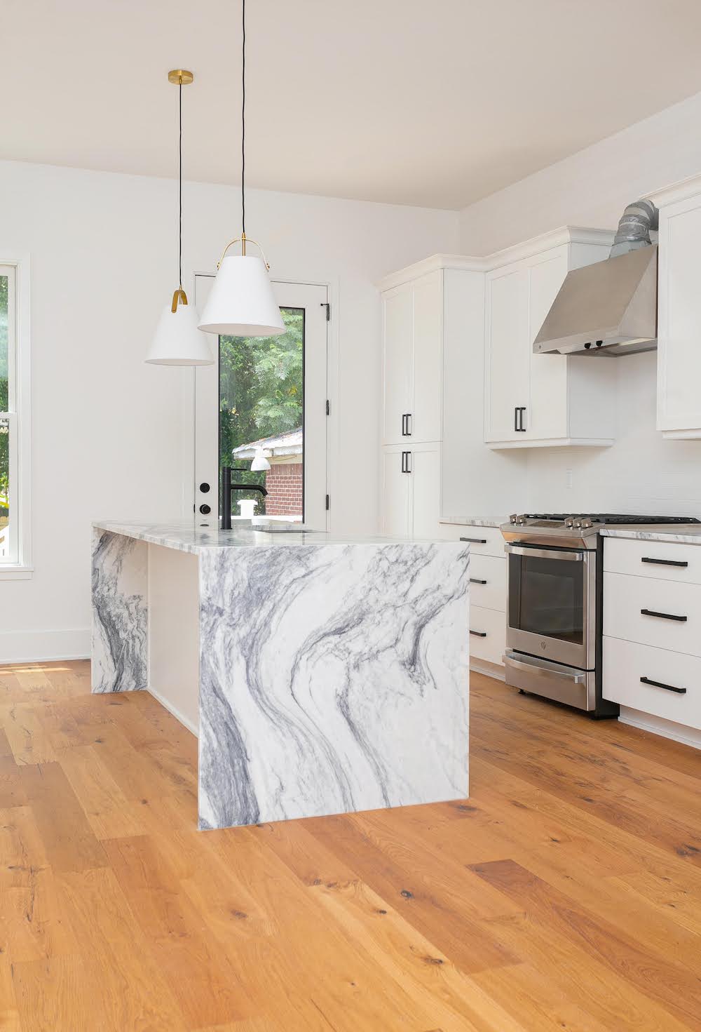Marble waterfall island, white cabinets with black handles, white kitchen pendants, custom home builder, Charleston, modern custom home, custom home